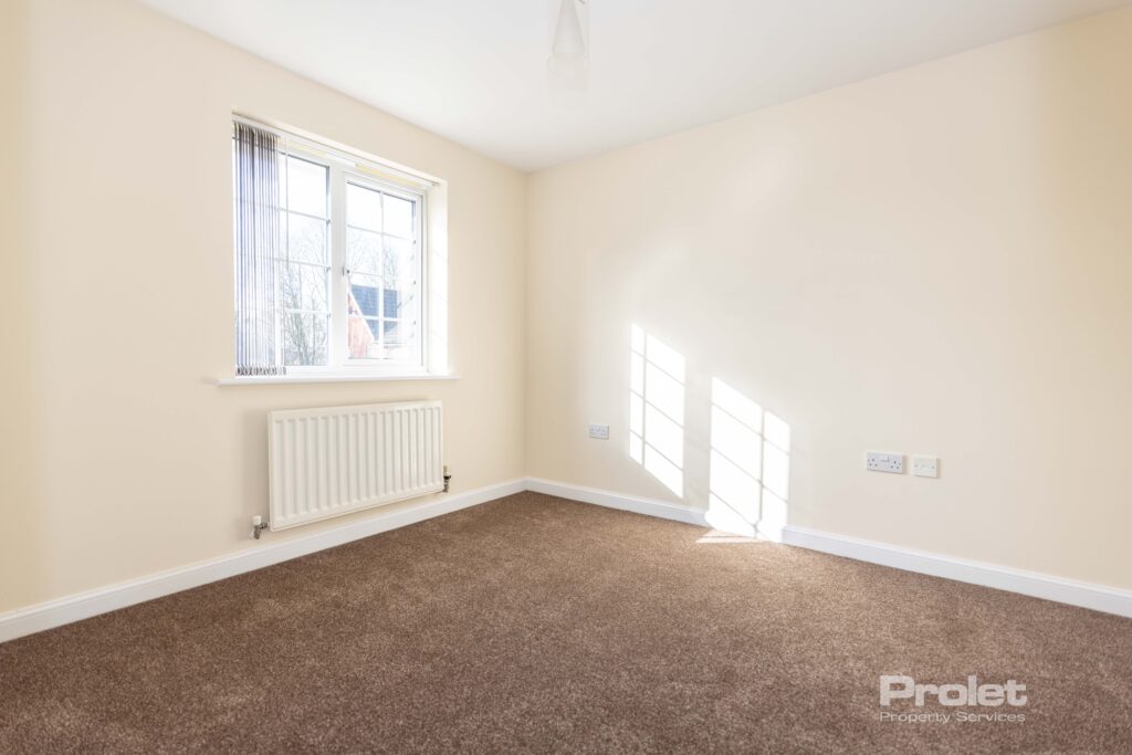 Large double bedroom with cream walls and brown carpet.