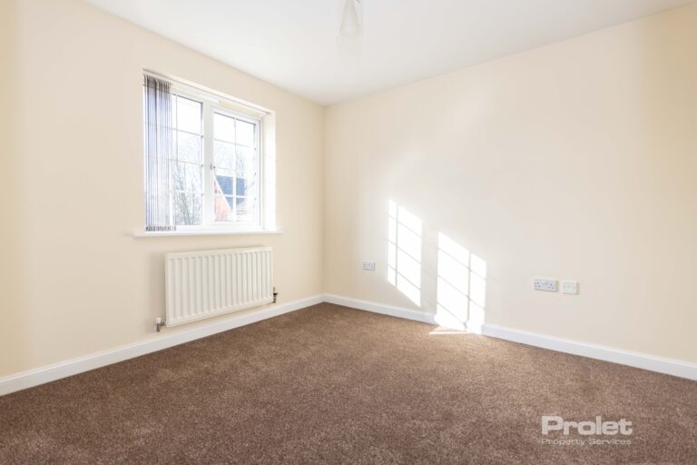 Large double bedroom with cream walls and brown carpet.