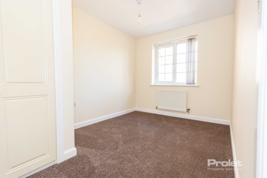 Large double bedroom with cream walls and brown carpet.