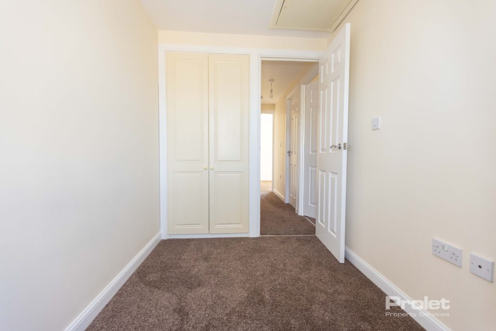 Single bedroom with cream walls and brown carpet