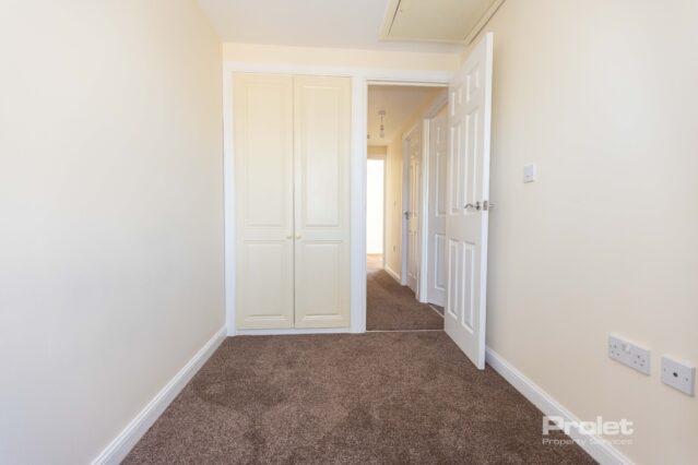 Single bedroom with cream walls and brown carpet