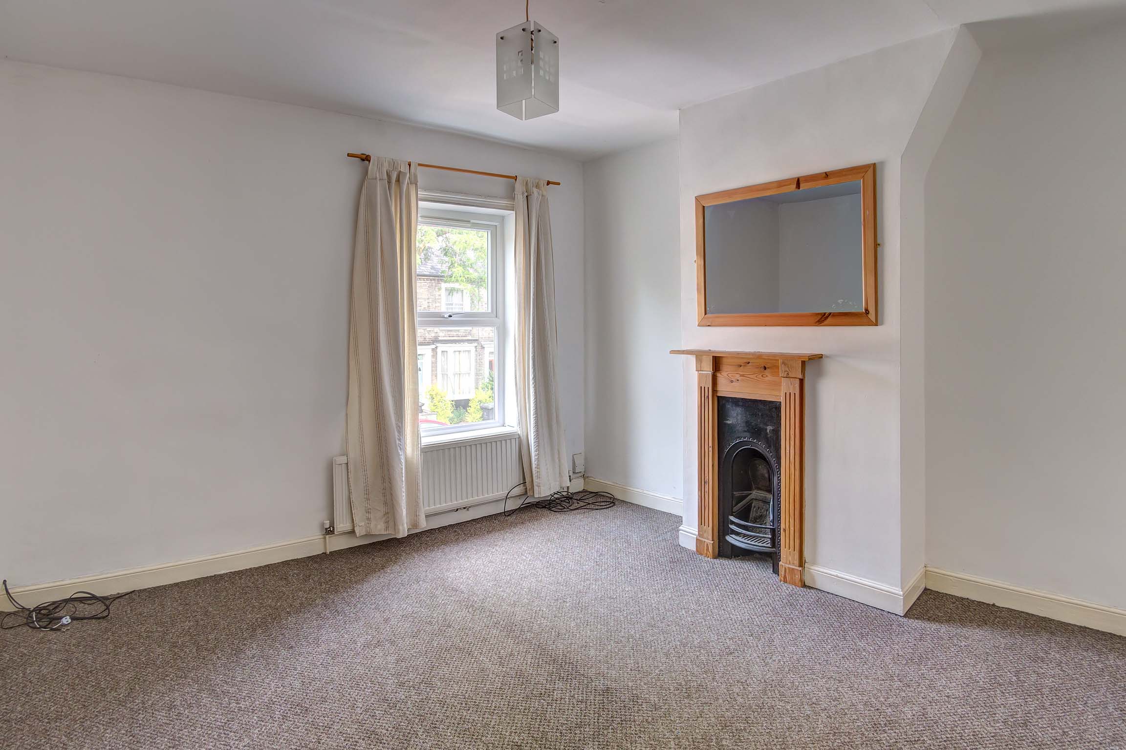 Brown carpet with off white walls and pine fireplace.