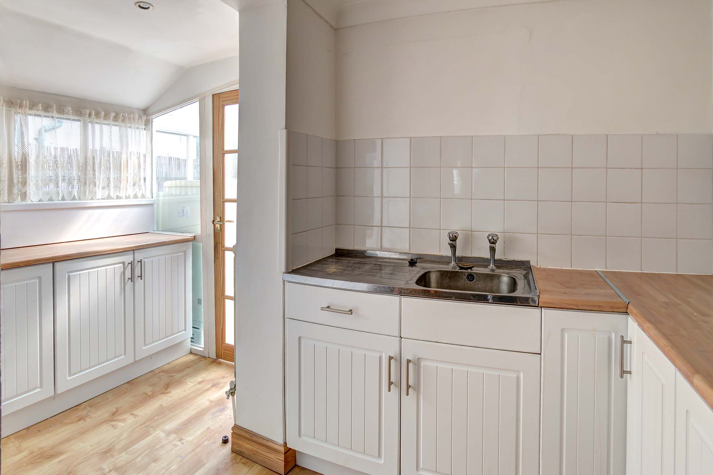Off white walls with stripped floor boards and white walls and units with pine effect worktops. Oven and fridge freezer