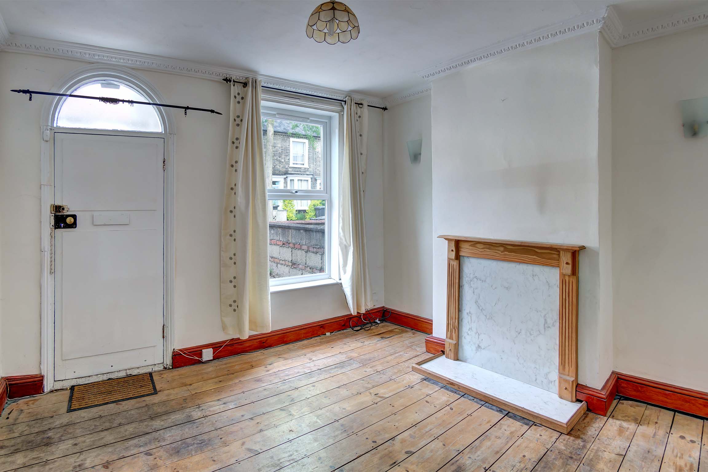 Off white walls with stripped floor boards and fireplace.