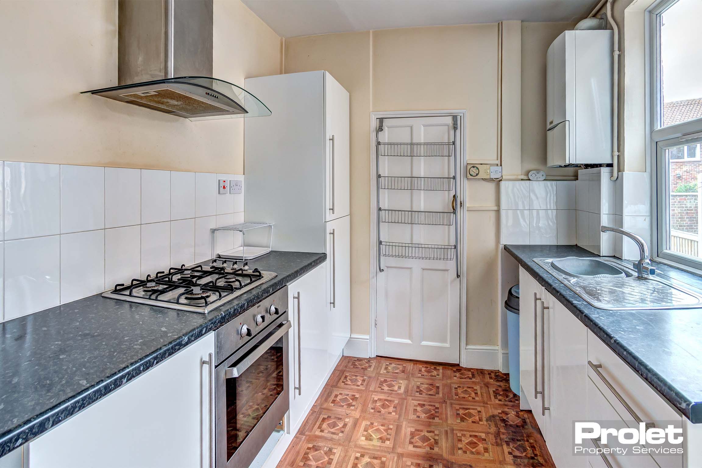 Wide galley kitchen with white cabinets and white goods