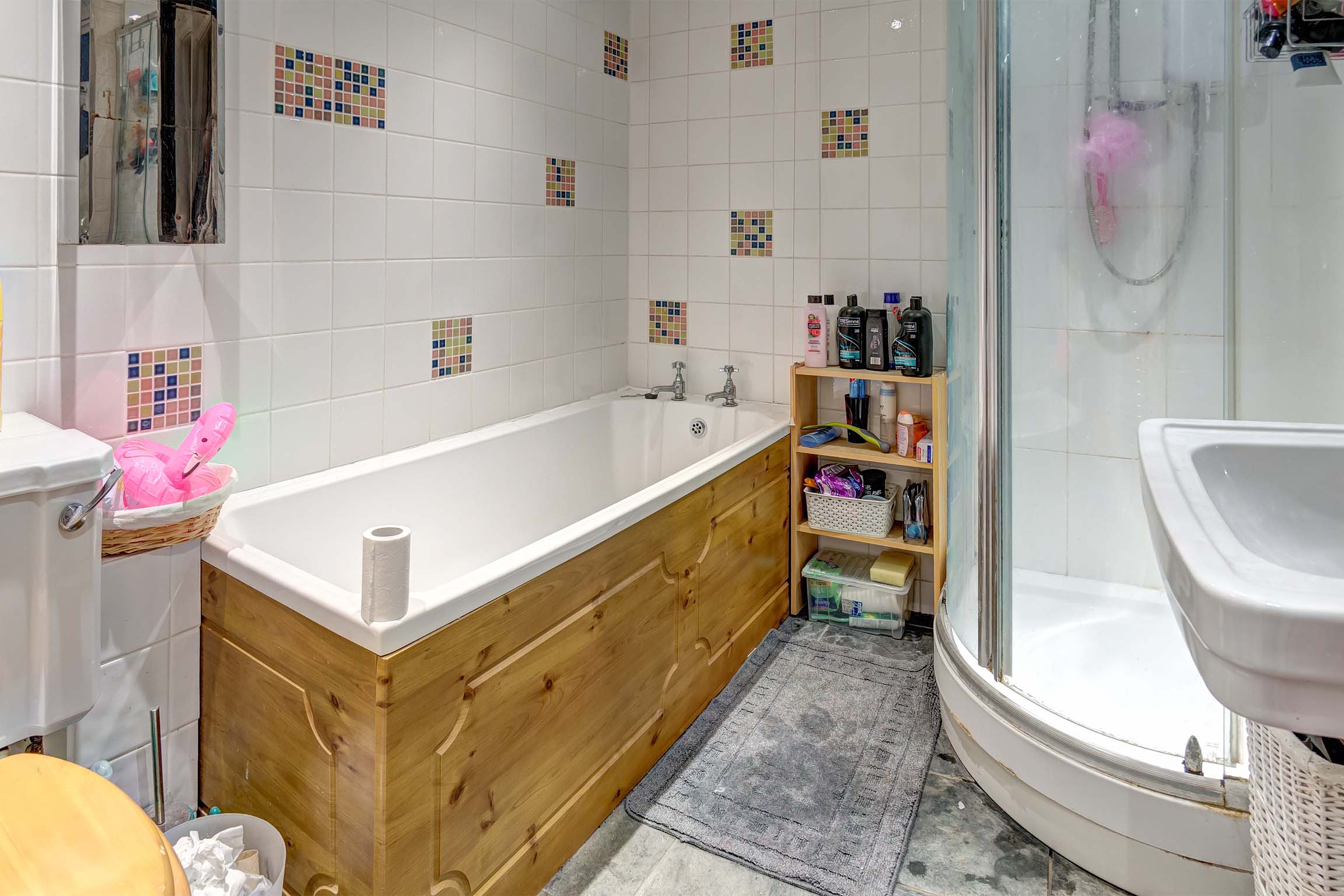 Bathroom with grey tiled floor, bath, and shower cubicle