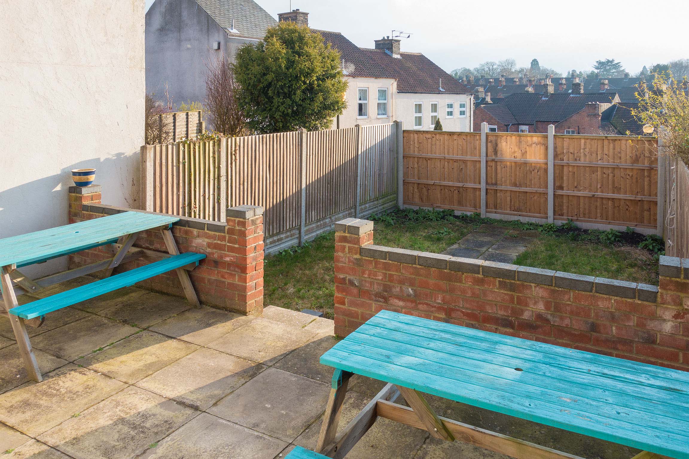 Garden area with wooden fence and brick wall on the raised patio.