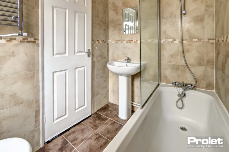 Modern tiled bathroom with shower over bath and pedestal sink