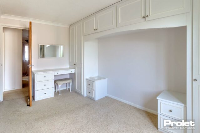 Cream carpet, off white walls with built in over bed wardrobes and dressing table