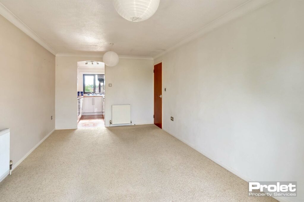 Cream carpets and magnolia walls leading to kitchen