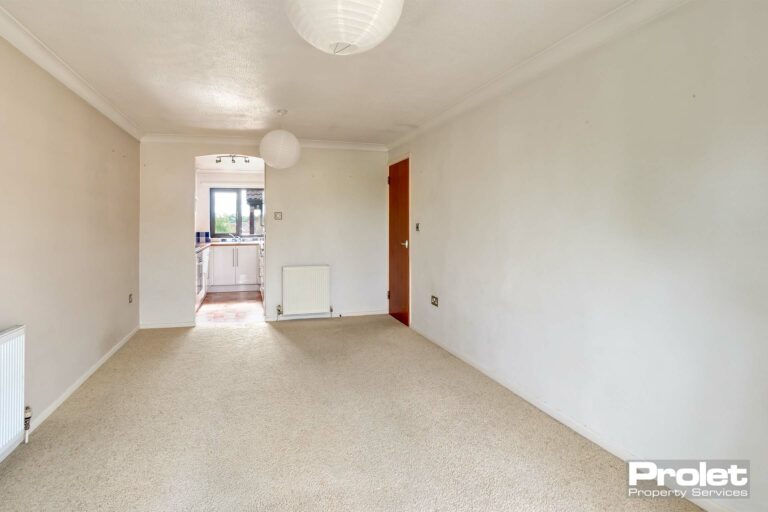 Cream carpets and magnolia walls leading to kitchen