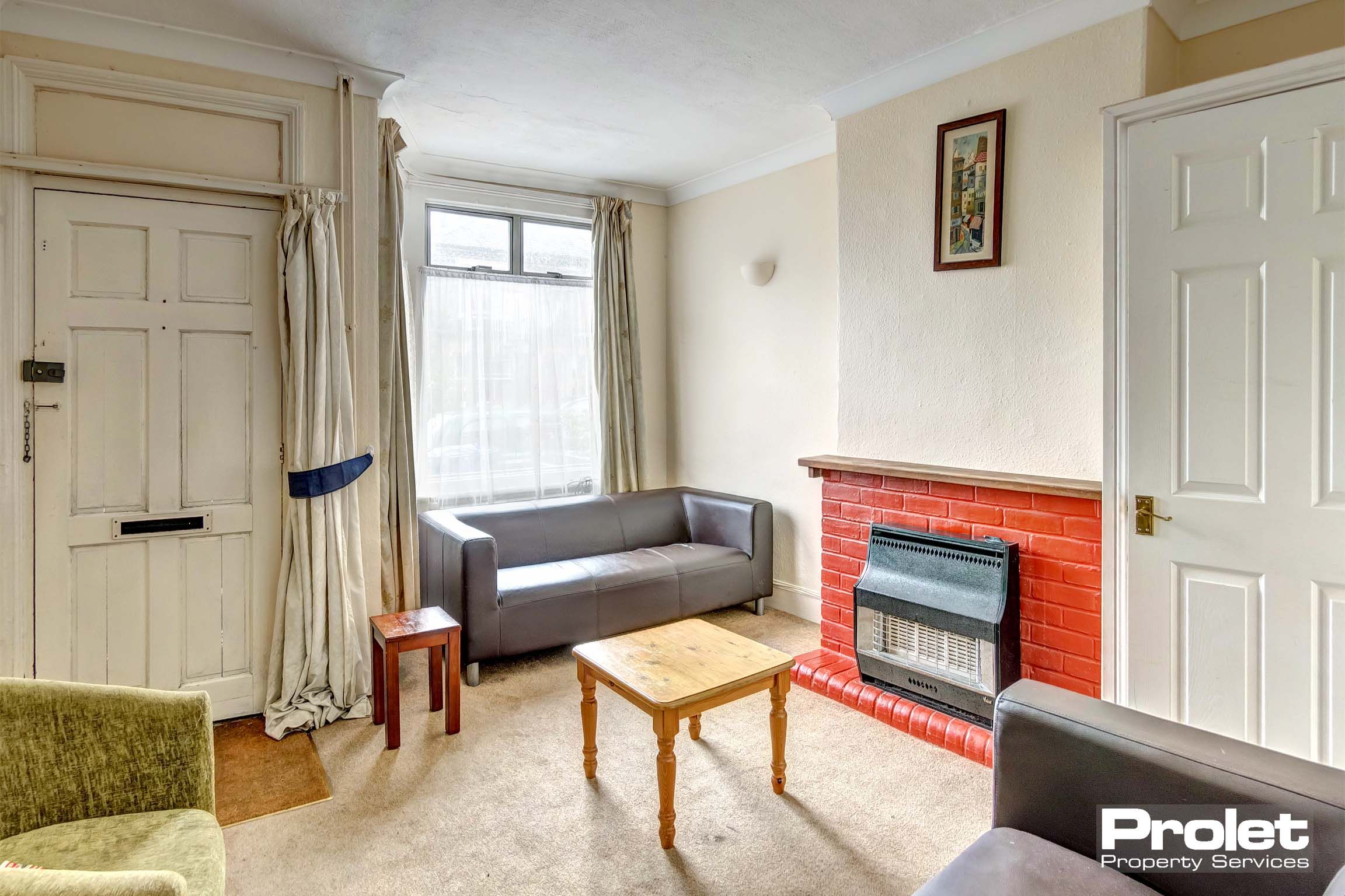 Lounge area with fireplace, two leather sofas and a fabric chair.