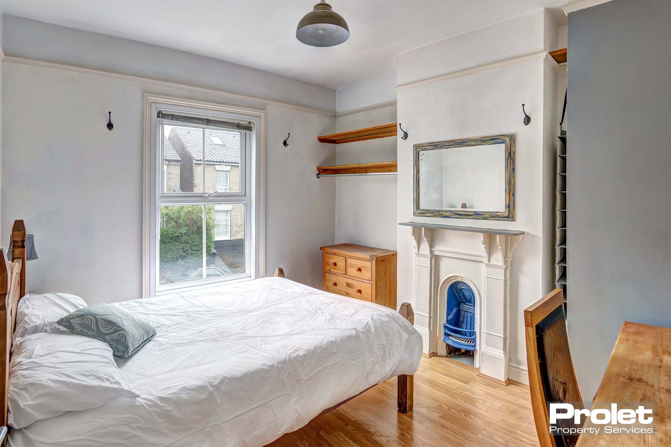 Double bedroom with wooden flooring and decorative fireplace