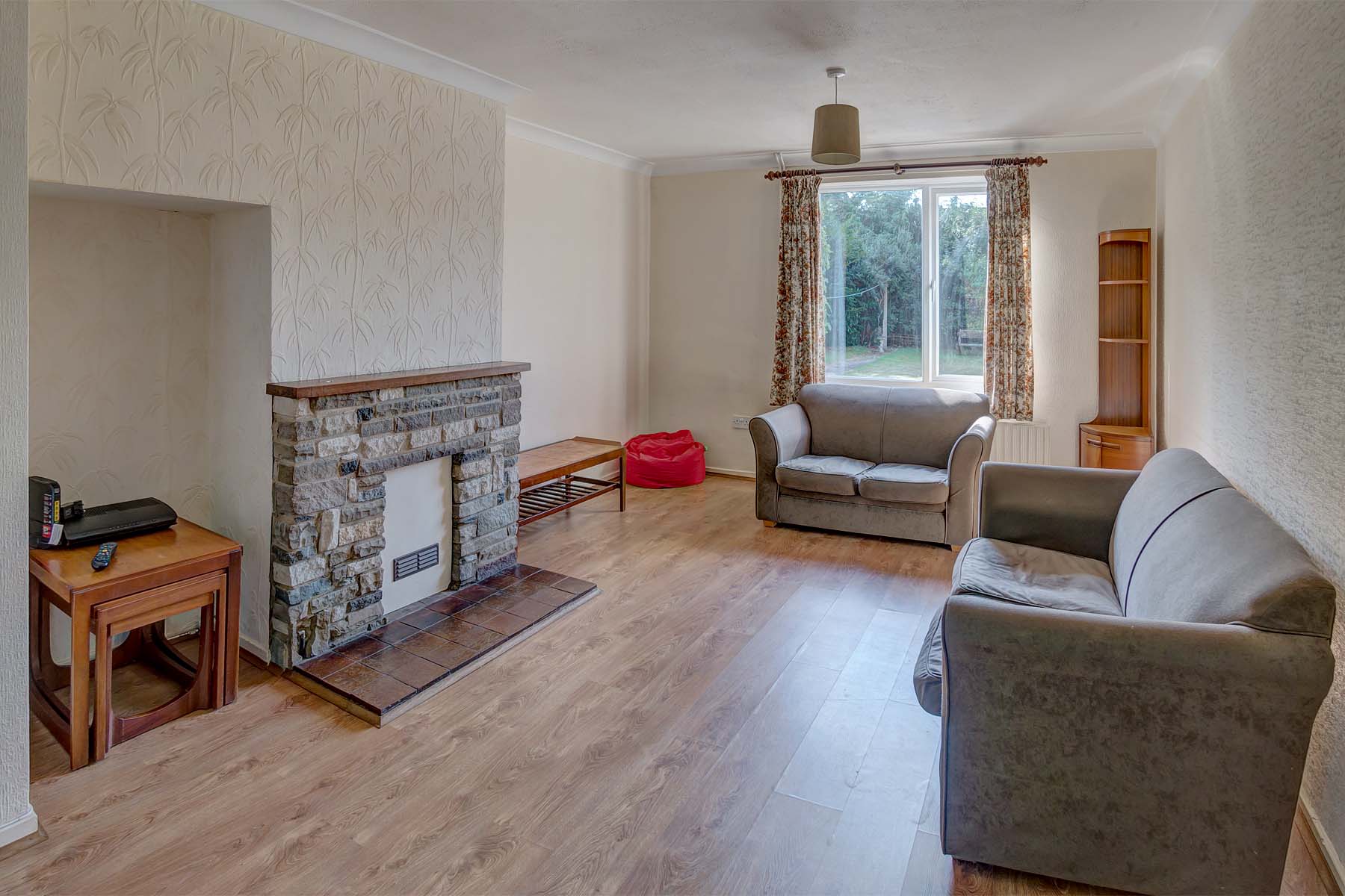 Lounge area with wooden effect lino flooring, two fabric sofas and a decorative fireplace.