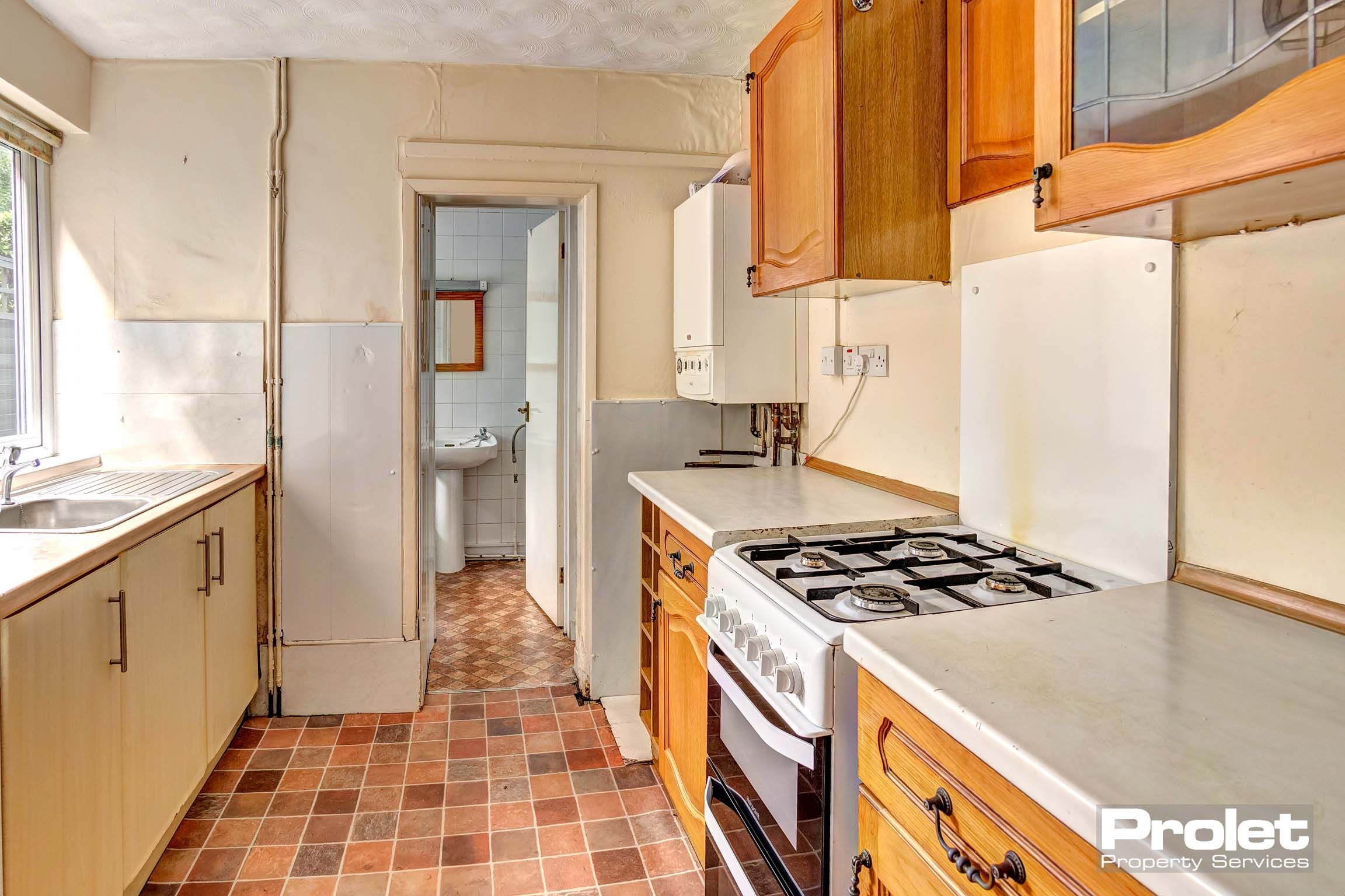 Galley style fitted kitchen with wooden cupboards and a light grain coloured worktop.