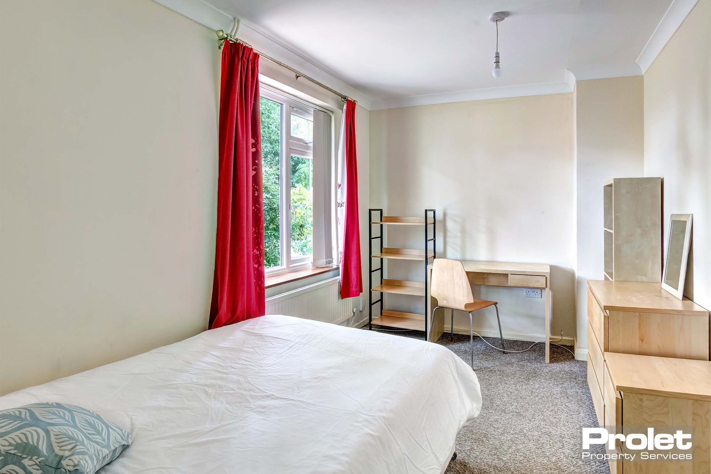 Double bedroom with wooden desk, bookshelf and chest of drawers.