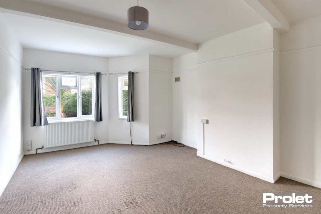 Large living area with beige carpet, and white walls