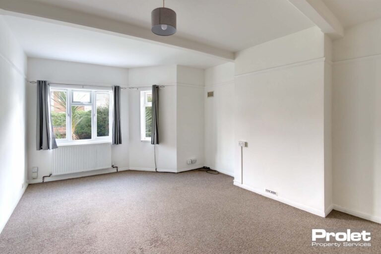 Large living area with beige carpet, and white walls