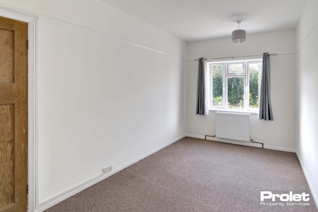 Double bedroom with beige carpet, and white walls