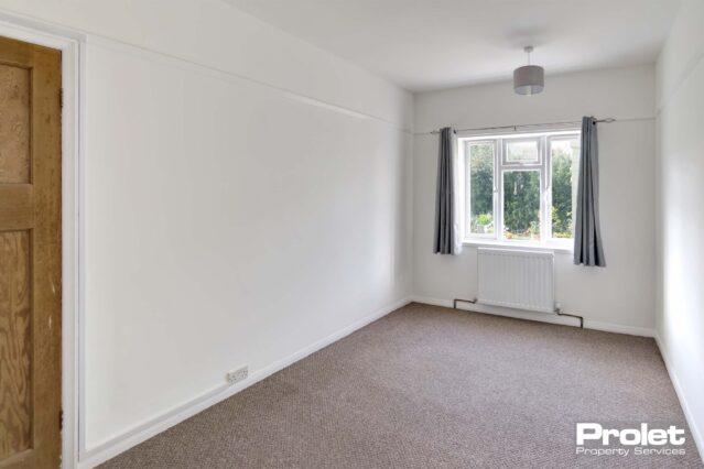 Double bedroom with beige carpet, and white walls