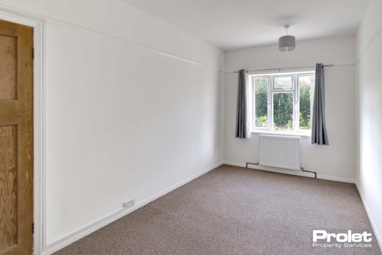 Double bedroom with beige carpet, and white walls