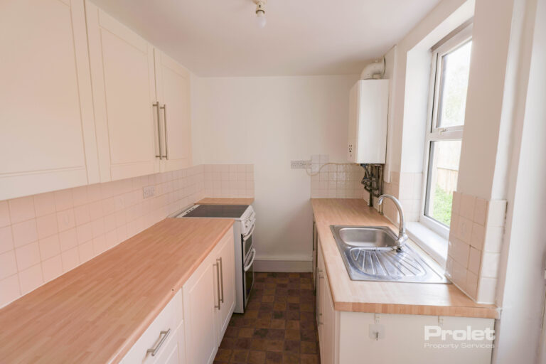 Galley style kitchen with cream cabinets, and wood worktop