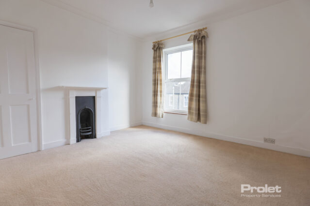 Front double bedroom with white walls, cream carpet, built in cupboard, and period fireplace