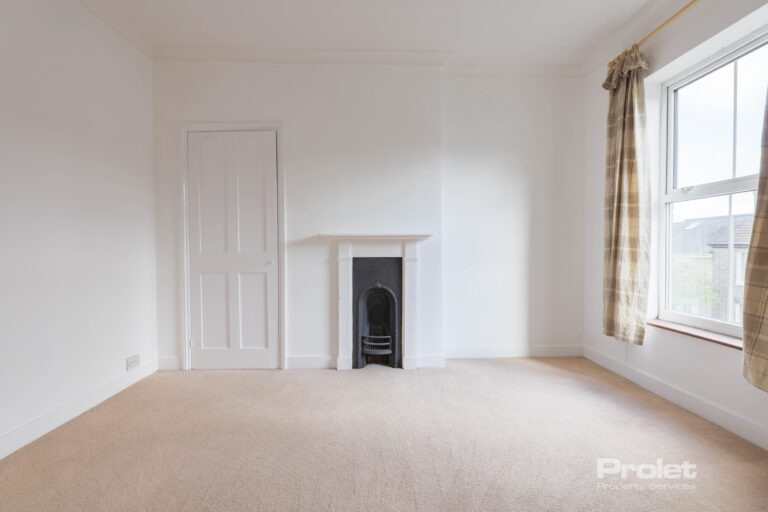 Front double bedroom with white walls, cream carpet, built in cupboard, and period fireplace