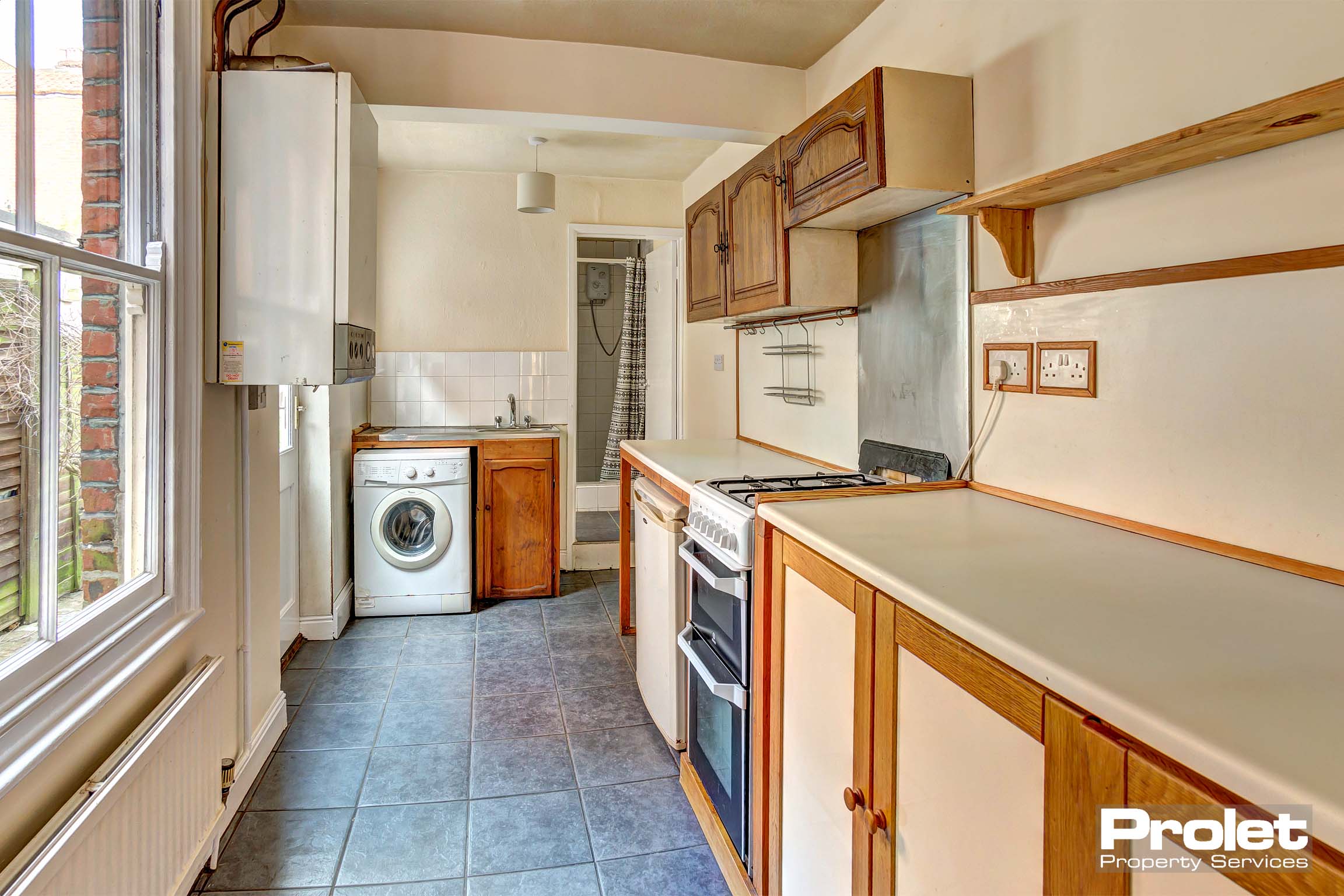 Galley kithen with wooden cabinets, and tiled floor