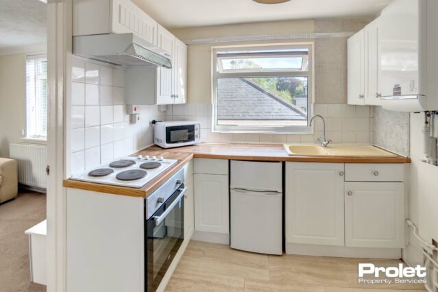 Laminate flooring, white units and beech effect work top with cooker, fridge freezer and microwave