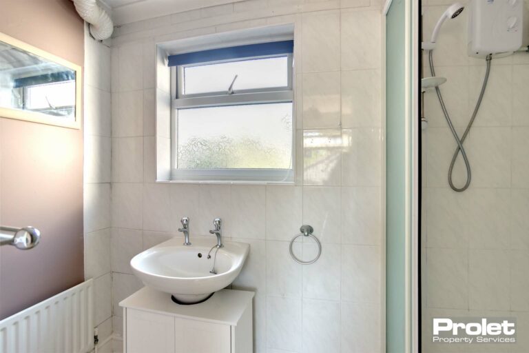 Bathroom with white tiled walls and wall painted mocha with sink and shower cubicle