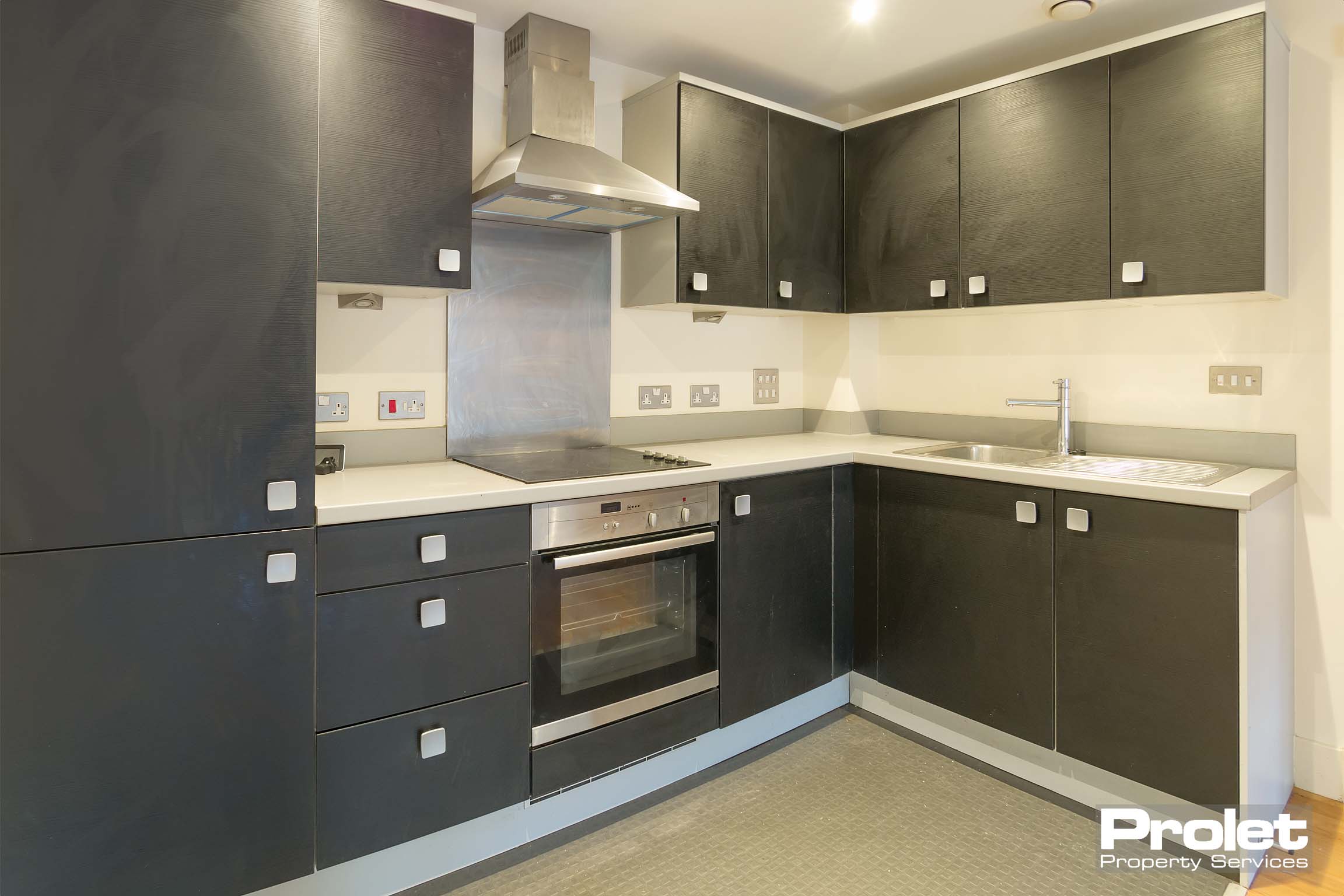 Built in black building with white worktop. Integrated fridge freezer, hob and oven