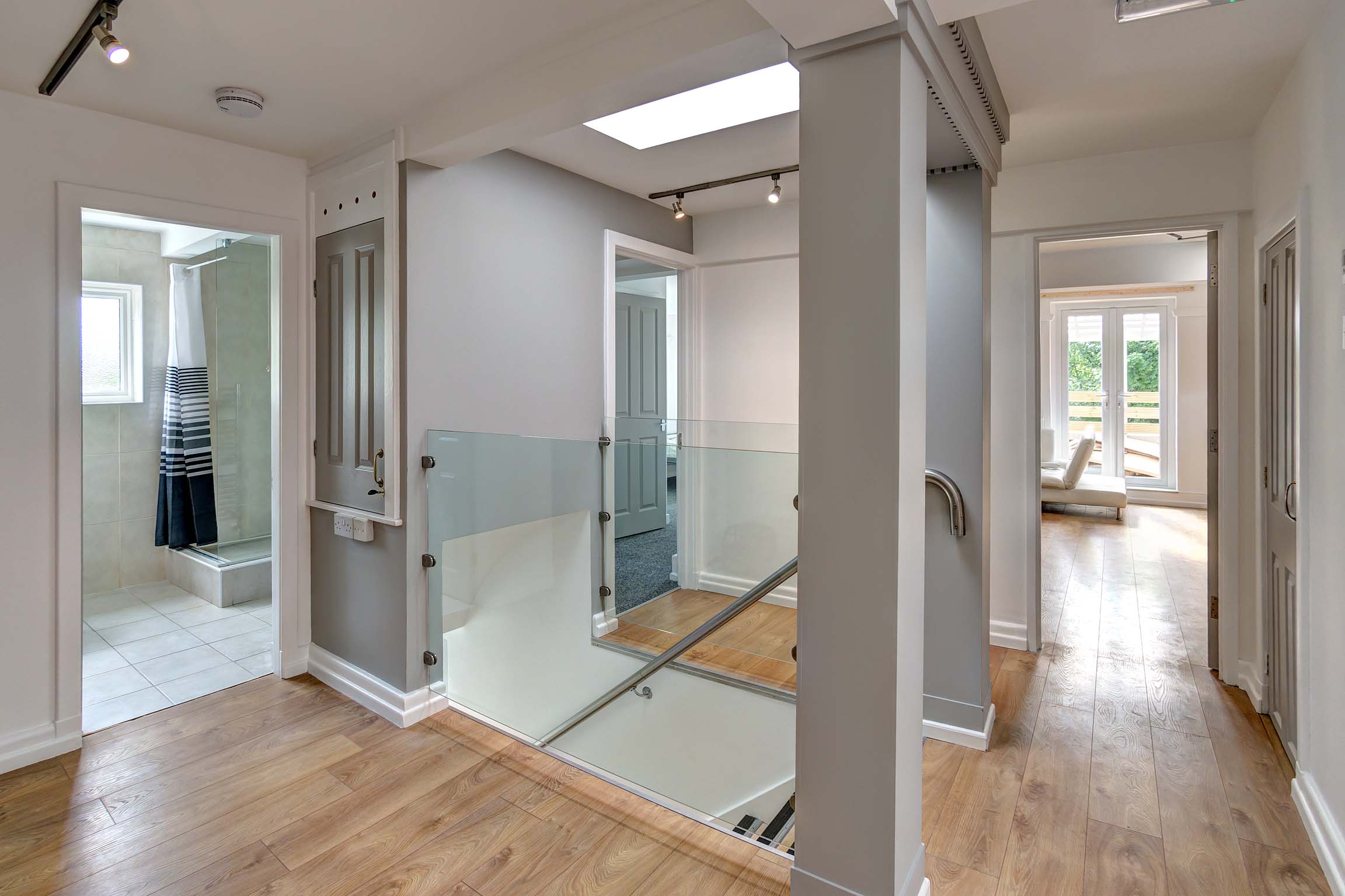 Landing area with glass safety wall and wooden flooring.