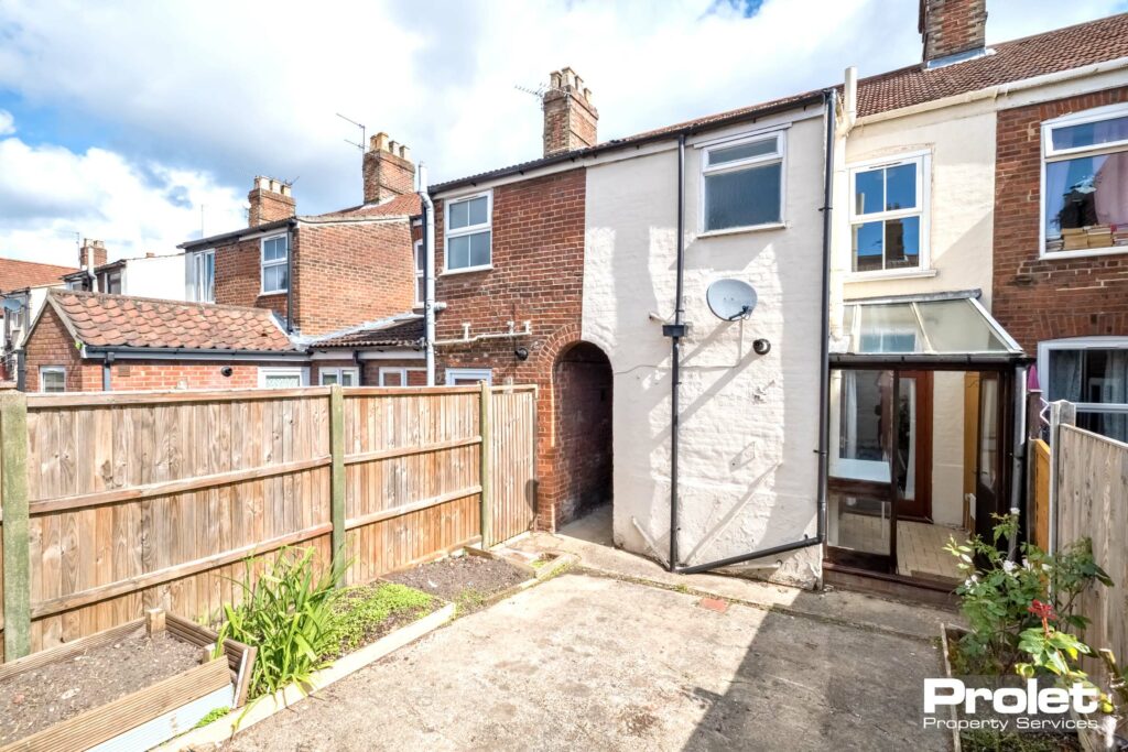 Step up to paved garden with flower beds and alley way to front of property.