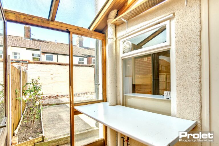 Lean to off dining room with glass walls and white shelf leading to rear garden