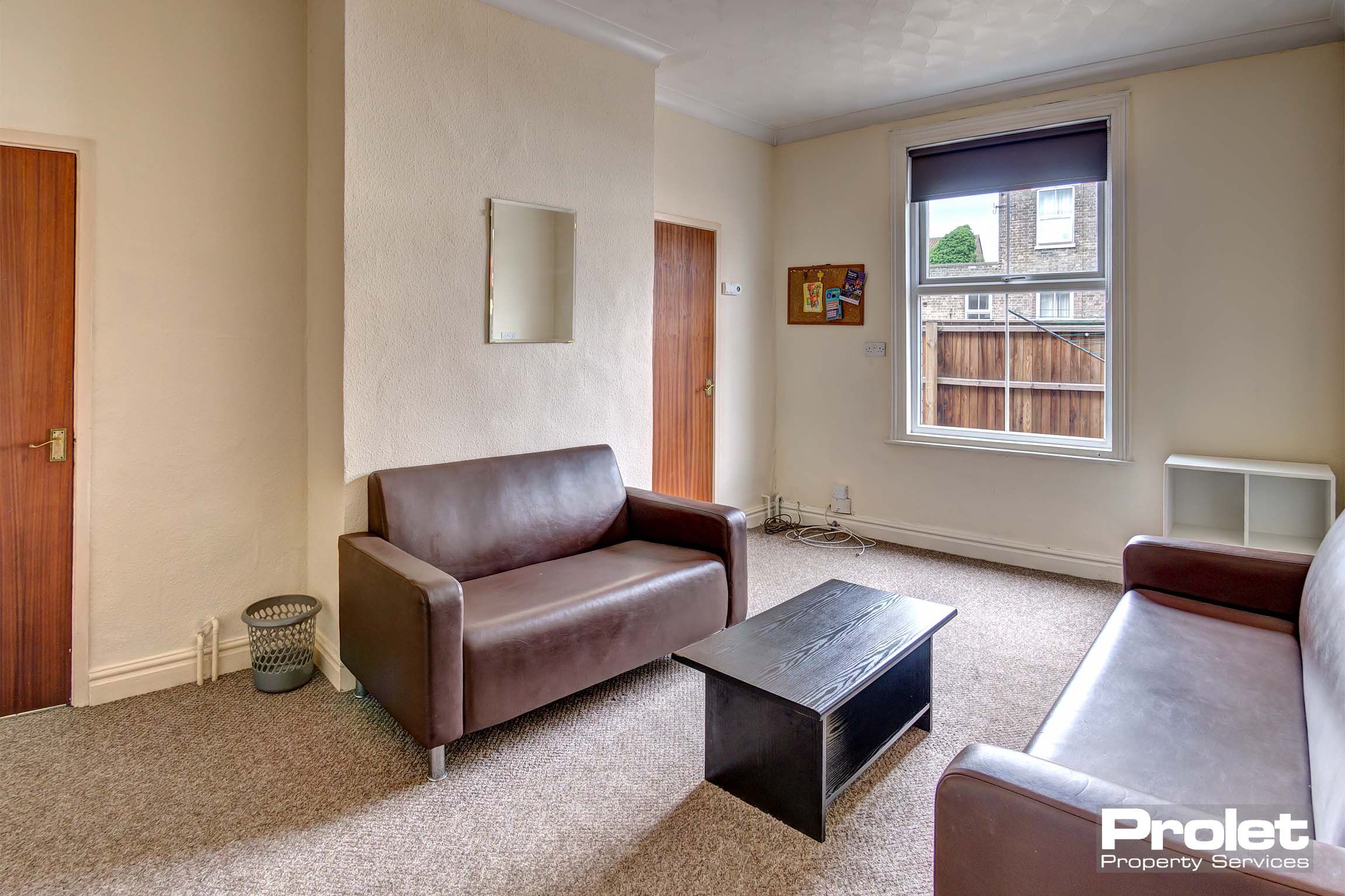Lounge area with light brown carpet, two brown leather sofas and a brown coffee table.