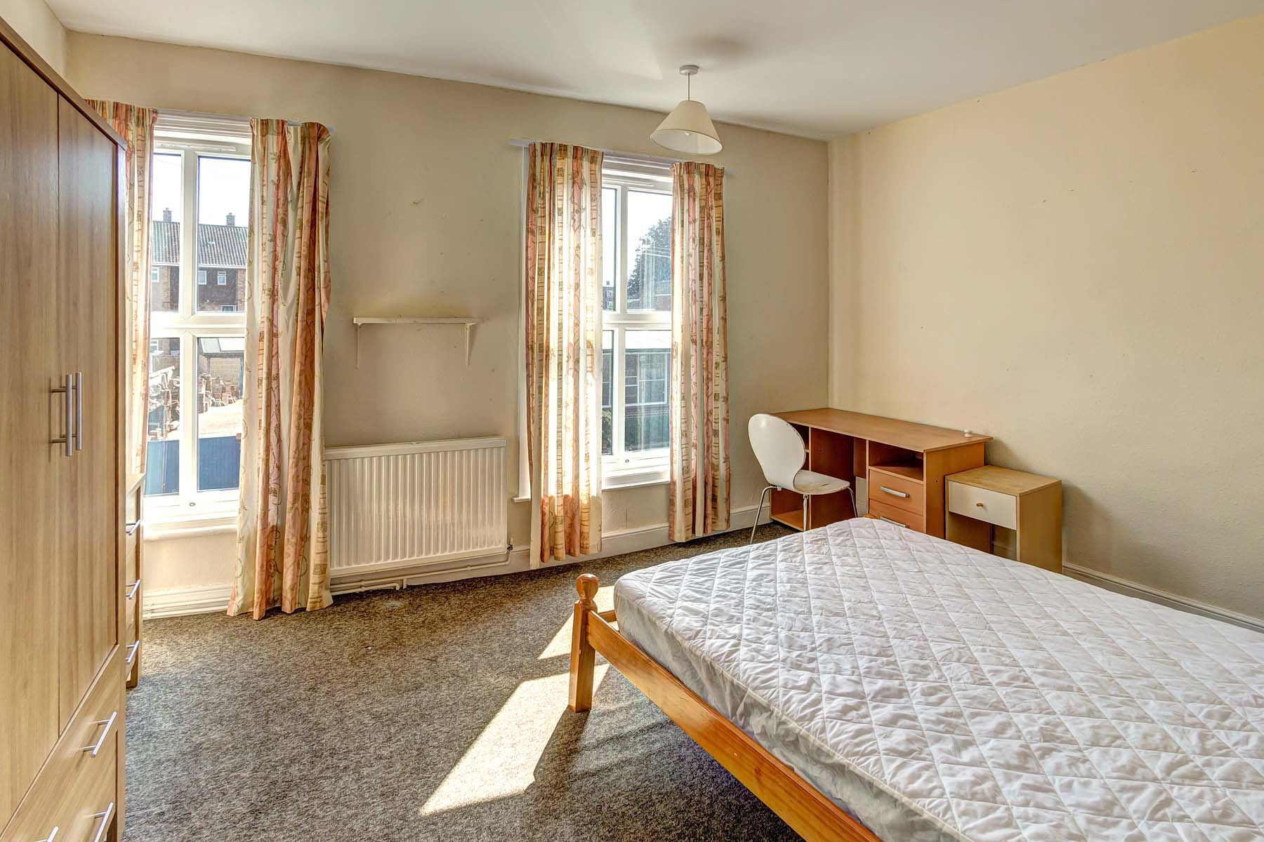 Bedroom with double bed, two windows, and wooden desk