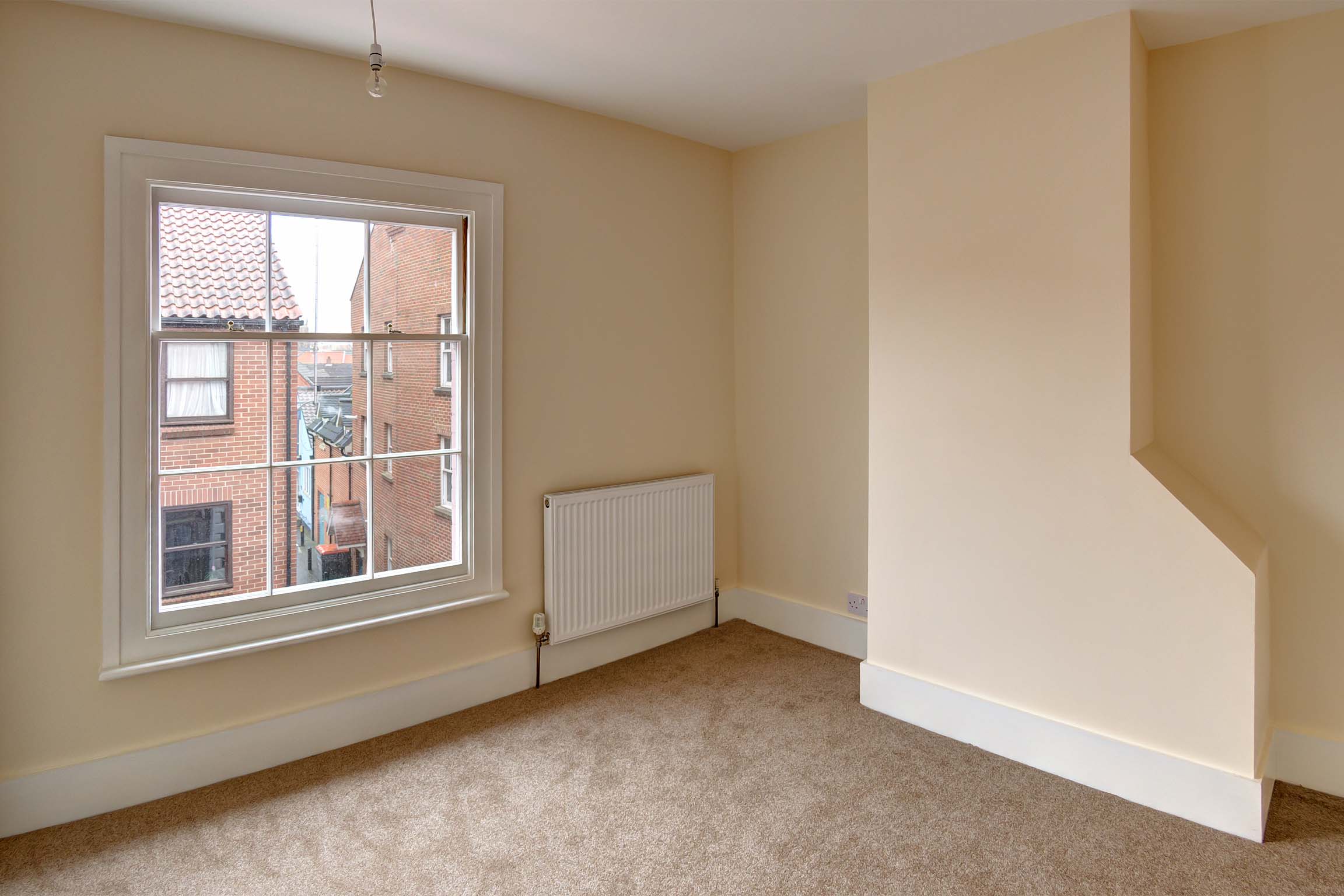 Magnolia painted walls with brown carpet and traditional sash windows