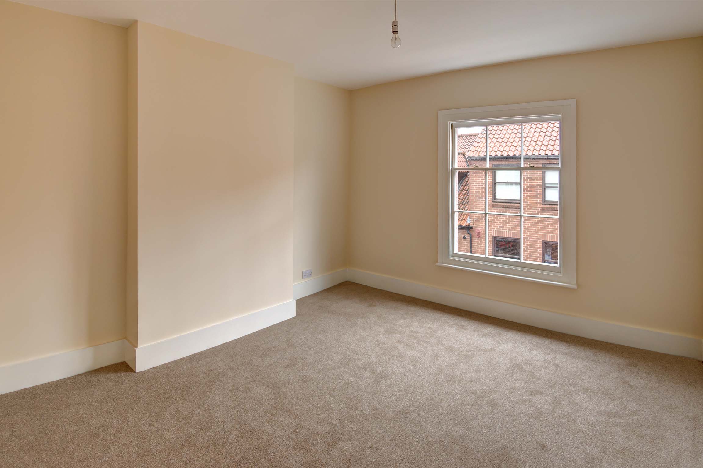 Magnolia painted walls with brown carpet and traditional sash windows