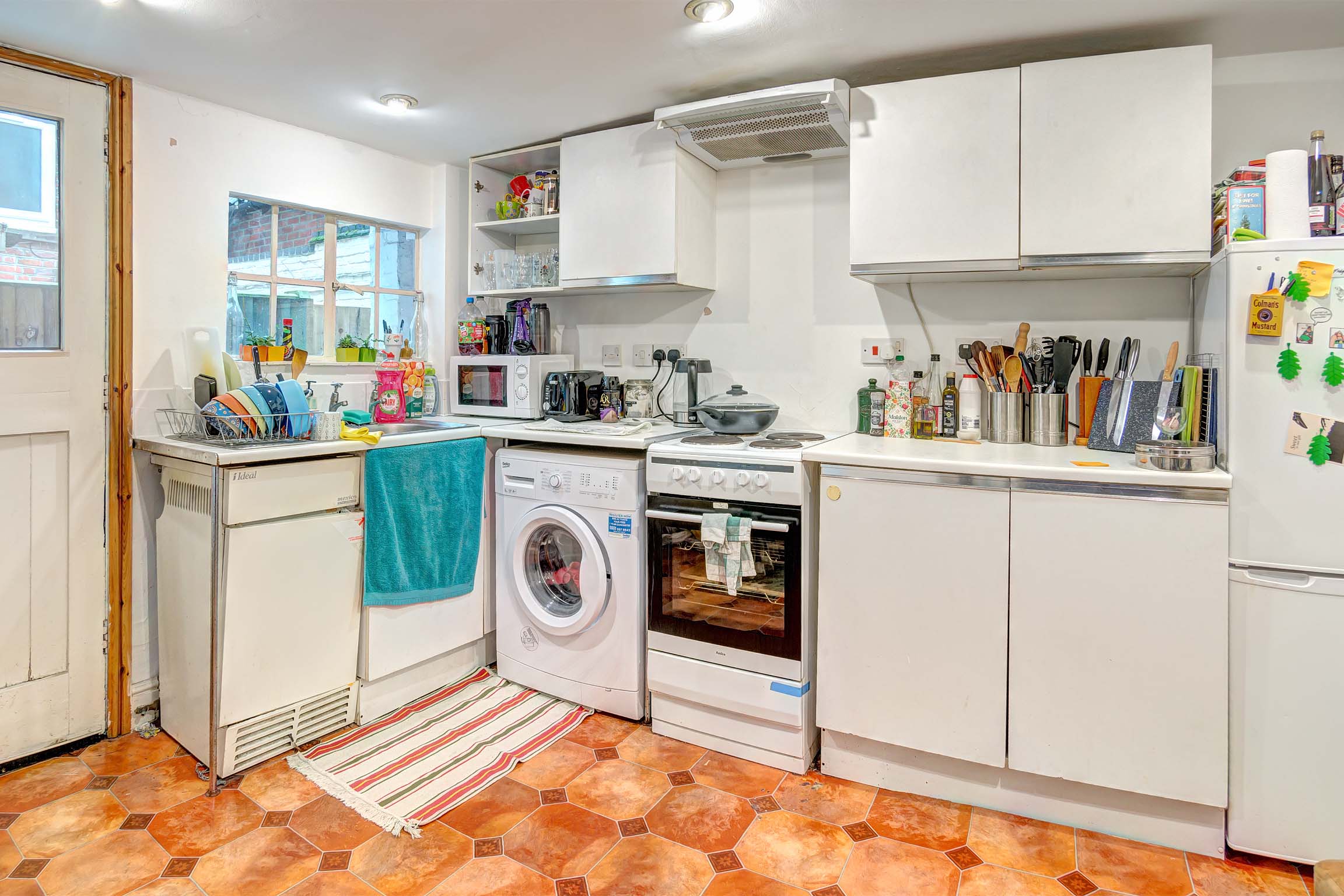Kitchen with white goods, cabinets, and worktop