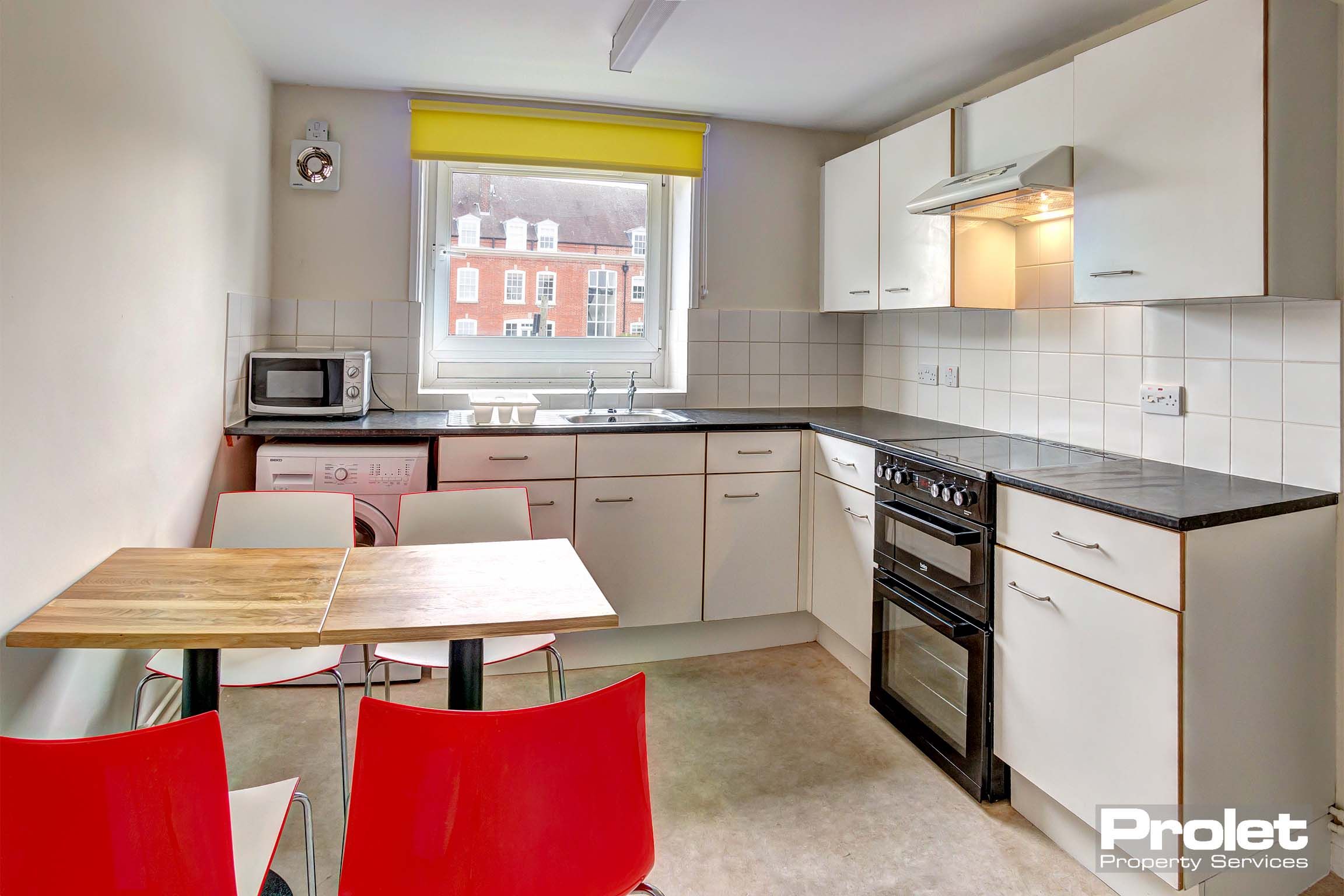 Kitchen with white cabinets, large appliances, and dining set
