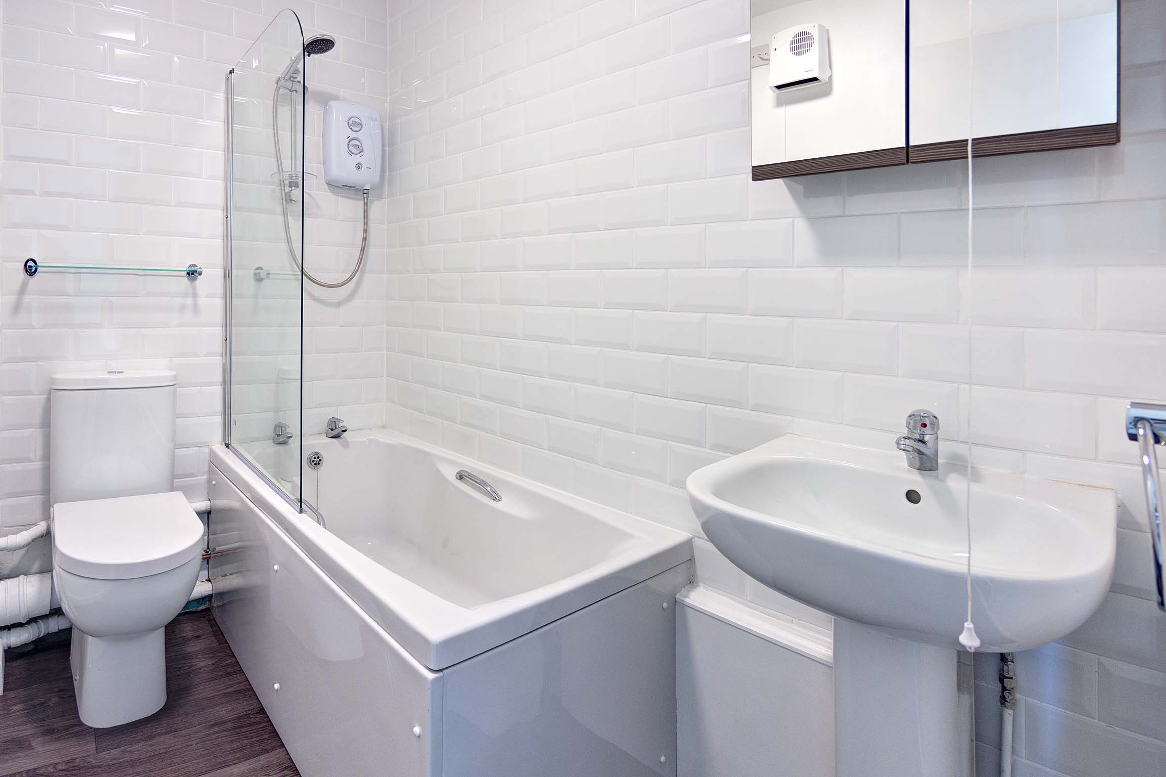 White bathroom with white suite and shower over bath