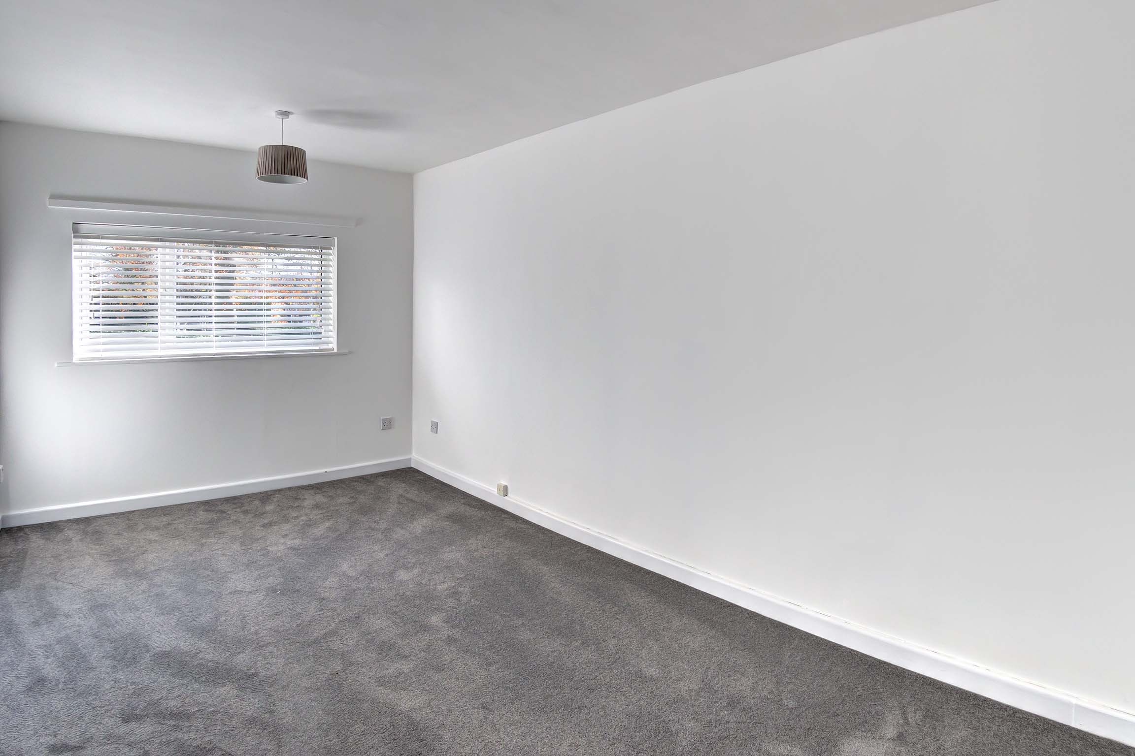 Bedroom with white walls, white blinds and grey carpets