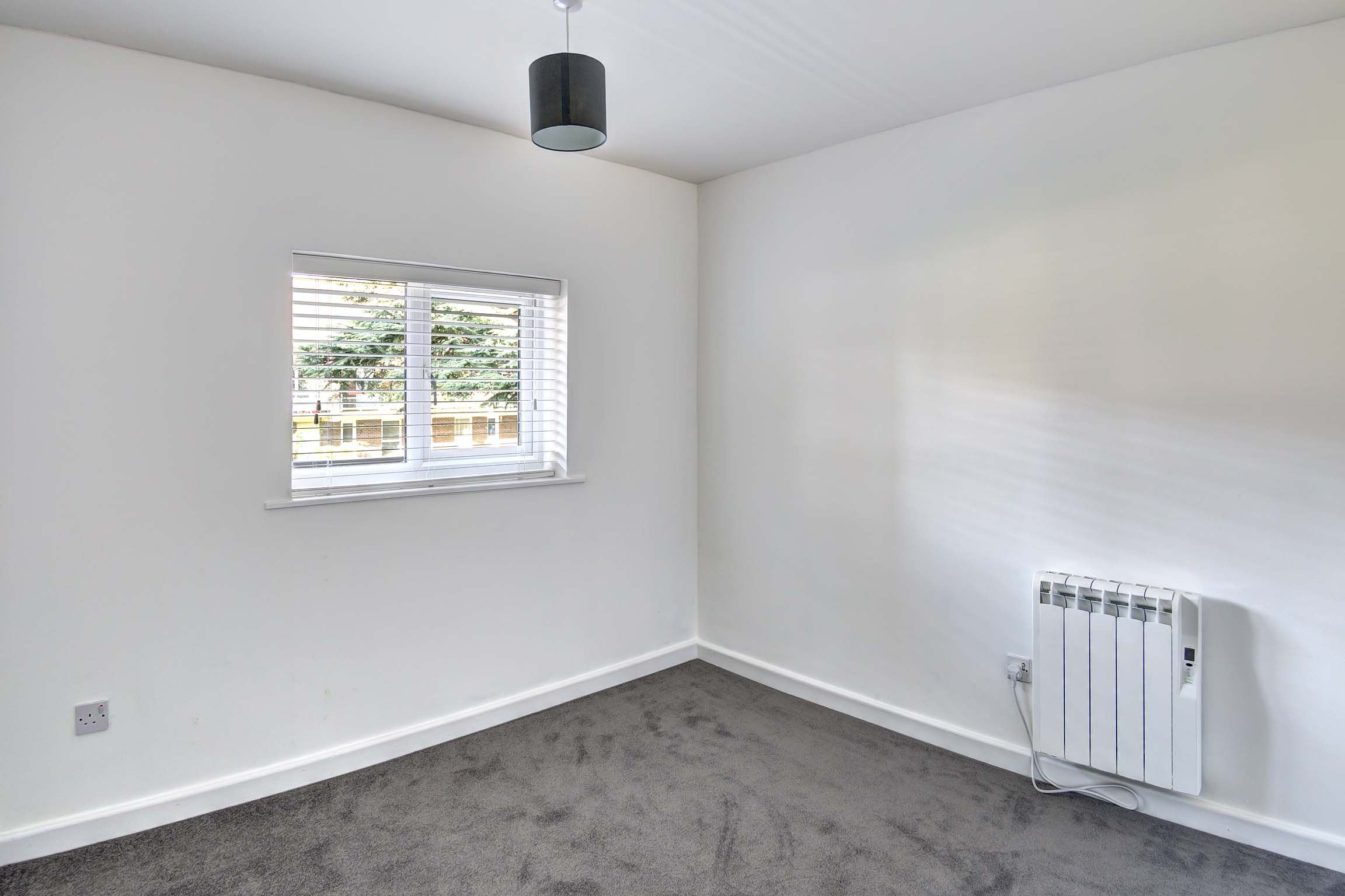 Bedroom with white walls, white blinds and grey carpets