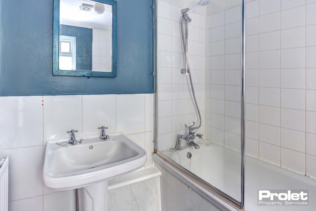 White bathroom suite with shower over bath and blue walls