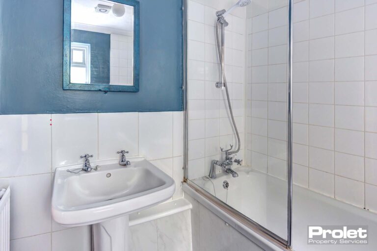 White bathroom suite with shower over bath and blue walls