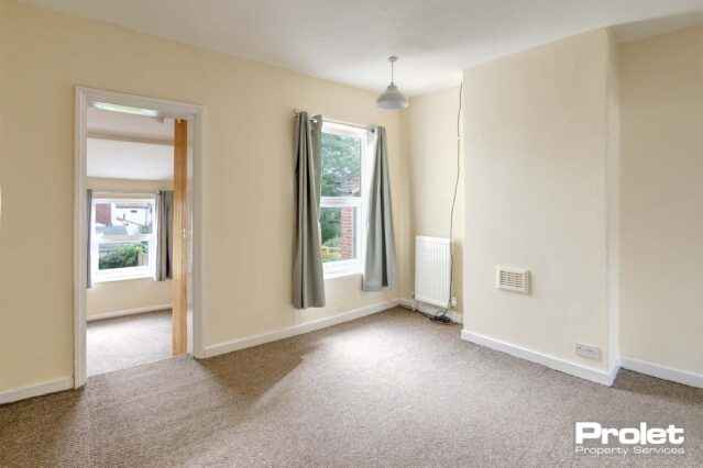 Upstairs bedroom with cream walls and beige carpet. Leading to box room.
