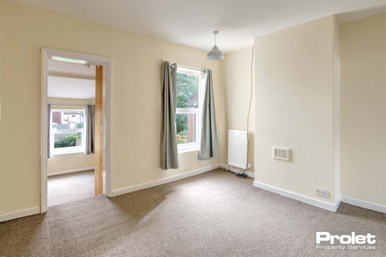 Upstairs bedroom with cream walls and beige carpet. Leading to box room.