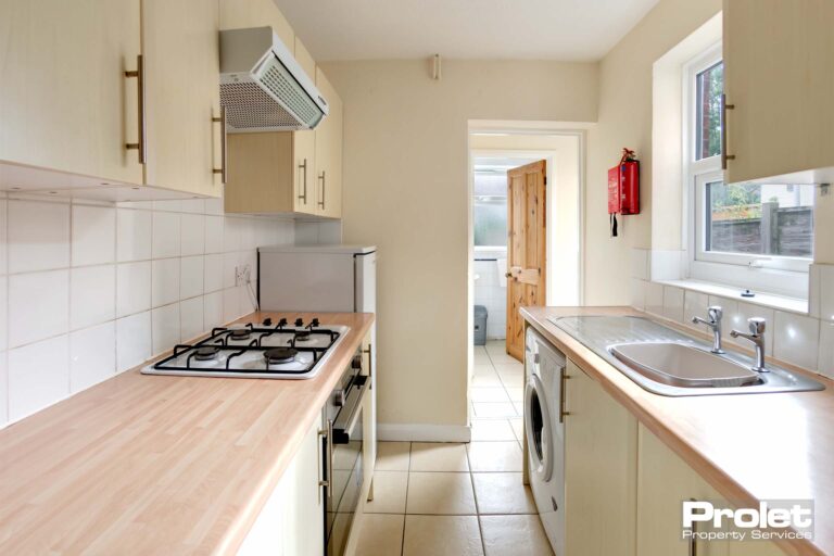 Galley kitchen with integrated oven, and gas hob. Wood effect worktops and cream cabinets.