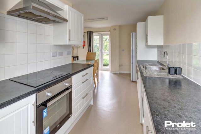 Modern kitchen with white cupboards, and black worktops